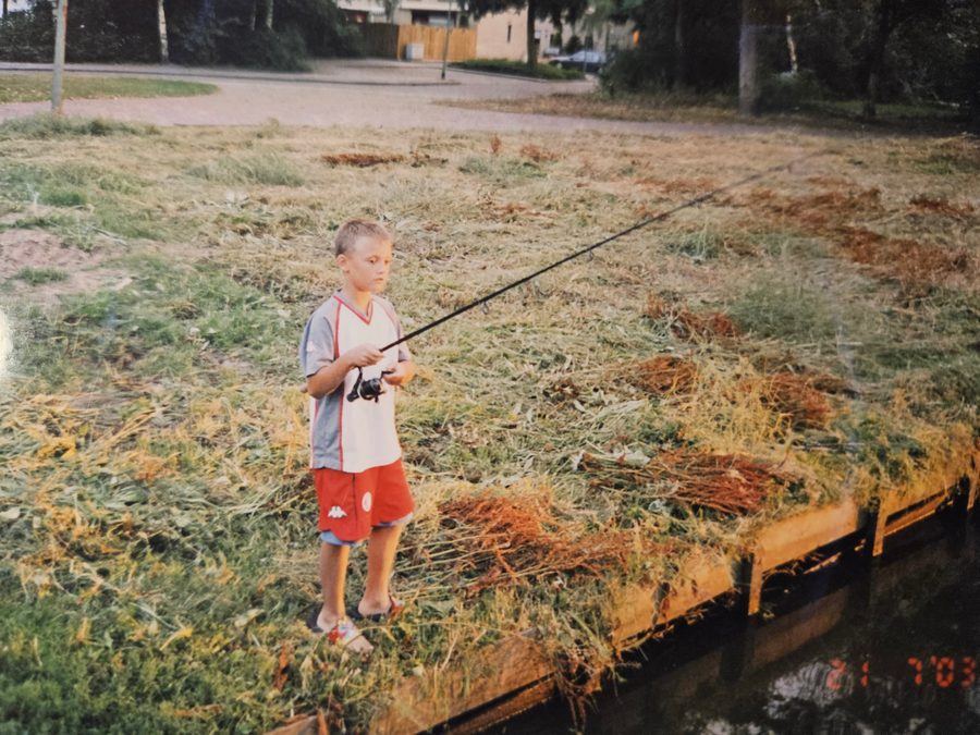 Diego als kind met een hengel op een grasveld bij het water